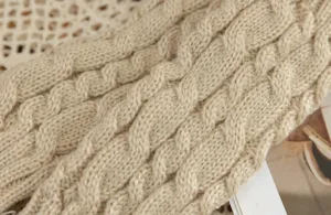 Beige cable knit fabric detail close up showing classic winter warm texture and soft material.