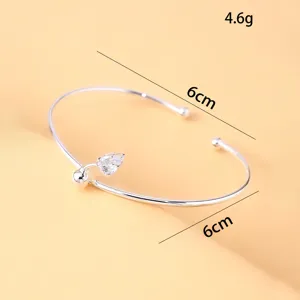 Nahaufnahme eines minimalistischen offenen Armreifs mit einem funkelnden Zirkonstein.