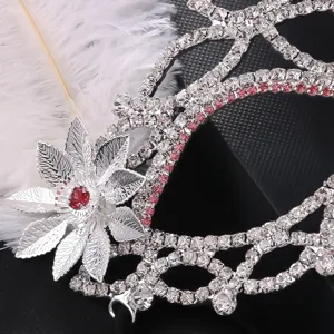 Detailed shot of a vintage court style masquerade mask with sparkling rhinestones and white feathers.