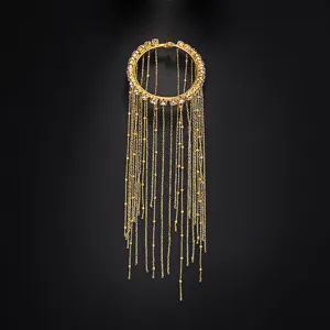 Dettaglio bracciale braccio strass oro, elegante catena pendente nappe moda donna chic.