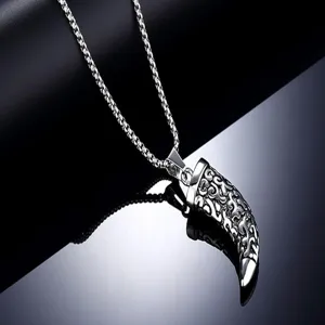 Vue détaillée d'un élégant collier pendentif dent de loup en acier inoxydable aux motifs gravés.