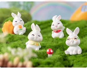Detailed shot of cute resin rabbit miniature figurines on green moss for DIY micro-landscape.