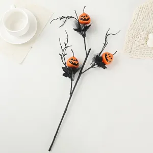 Detalle de rama negra de Halloween con caras de calabaza naranja y malla festiva.