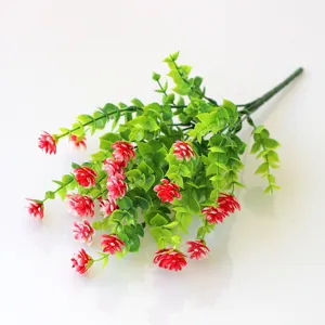 Detail view of artificial plastic eucalyptus leaves and red flower bouquet for wall decor.