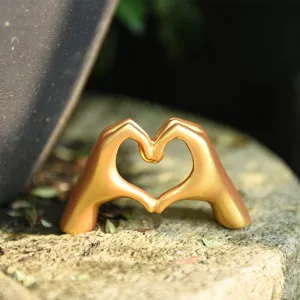 Gold heart hand gesture sculpture detail shot, luxury Nordic style tabletop decor gift.