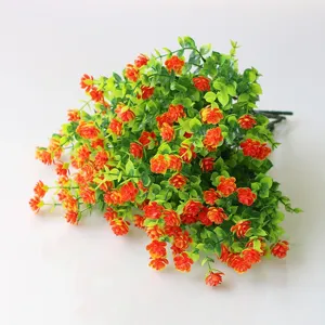 Artificial plastic plant detail showing lush green leaves and vibrant orange flowers for home decor.