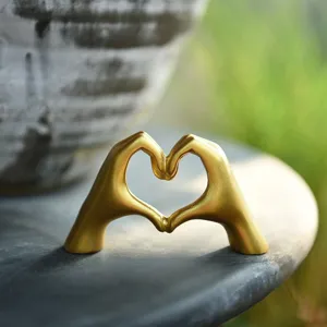 Golden heart gesture statue detail, minimalist Nordic decor piece for desk or modern home.