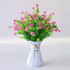 Artificial flower detail closeup showing pink blossoms and green leaves in a white vase.