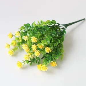 Detailed view of artificial yellow flower bouquet with green leaves for plant wall decor.