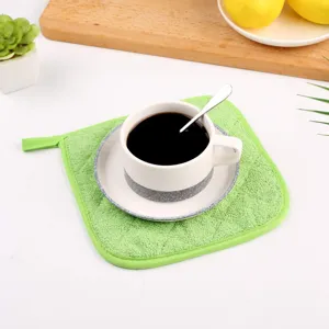Nahaufnahme der grünen Baumwoll-Frottee-Topfunterlage mit Kaffeetasse und Zubehör.