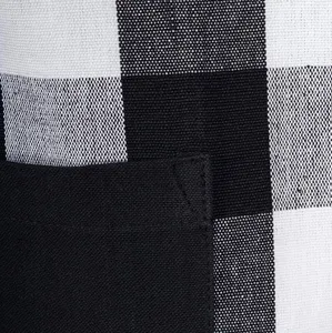 Close-up detail of black and white plaid apron pocket, showing fine stitching and fabric texture.