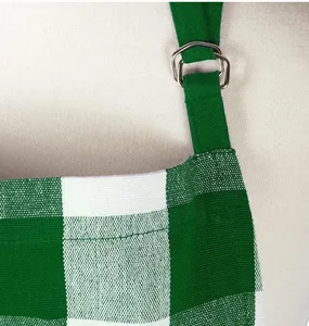 Green and white plaid apron shoulder strap detail, adjustable metal buckle fabric texture.