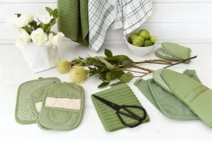 Vue détaillée de gants de cuisine verts et maniques présentés dans un décor naturel.