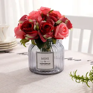 Detailed close-up of artificial rose bouquet with glass vase, elegant home decor item.