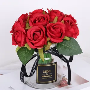 Artificial red rose bouquet in glass vase with black ribbon, home decor detail shot.