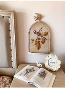 Detail view of the vintage birdcage wall decor with a swallow on top and botanical art.
