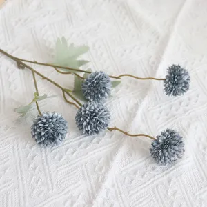 Detailaufnahme eines künstlichen Blumenstiels mit graublauen Pomponblüten und grünem Blatt.