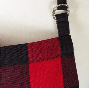 Close-up detail of red black buffalo plaid apron fabric with black strap and metal ring.
