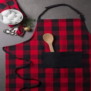 Detail view of the red and black buffalo plaid kitchen apron with pocket and wooden spoon.
