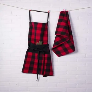 Detailed view of red and black buffalo plaid kitchen apron and matching towel set for cooking.