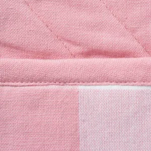 Cotton oven mitt fabric detail close-up showcasing soft pink plaid texture and stitching.