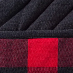 Close-up detail of quilted black fabric and red buffalo plaid kitchen pot holder texture.