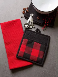 Detailed view of red and black cotton kitchen waffle towel and plaid pot holder set on table.