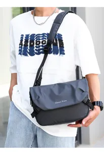 Men's dark grey oxford cloth crossbody bag detail view showing shoulder strap and flap design.