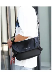 Detail shot of a black oxford cloth messenger bag worn crossbody, featuring minimalist style.