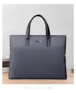 Dettaglio borsa uomo, tessuto oxford grigio scuro, manici resistenti e dettaglio in metallo.
