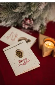 Détails de la carte de vœux de Noël avec un design de pomme de pin découpé et des points dorés.