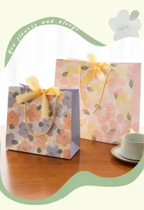 Vue détaillée de sacs cadeaux en papier fleuris avec des rubans jaunes élégants pour fêtes.