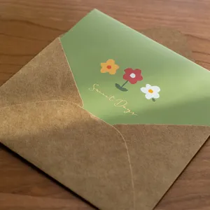 Green floral greeting card with gold foil text inside kraft paper envelope, main view