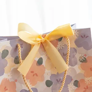 Sac cadeau en papier floral avec nœud ruban jaune, emballage élégant pour fête mariage