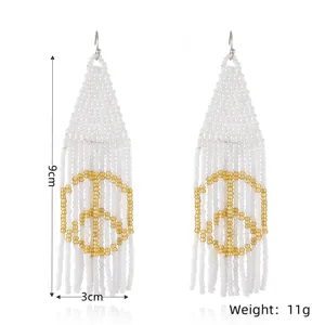 Detailed close-up of handmade white and gold beaded fringe earrings featuring a peaceful design.