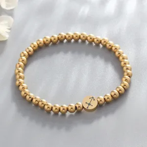 Close-up view of gold stainless steel beaded bracelet highlighting the zodiac charm detail.