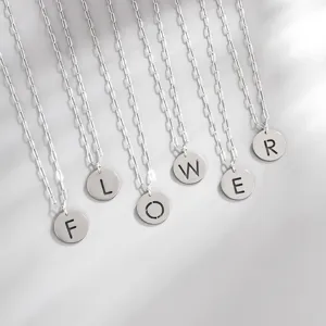 Detailed shot of silver stainless steel cutout letter pendant necklaces arranged neatly.