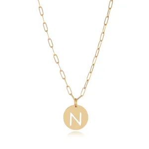 Close-up of gold-tone paperclip chain necklace featuring a cutout letter N round pendant.