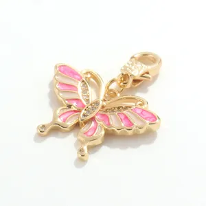Detalle de colgante de mariposa de esmalte bañado en oro, cristal brillante y dije rosa.
