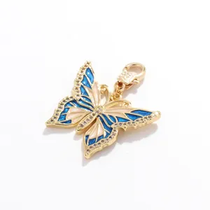 Primer plano detallado de un colgante de mariposa bañado en oro con esmalte azul y estrás.