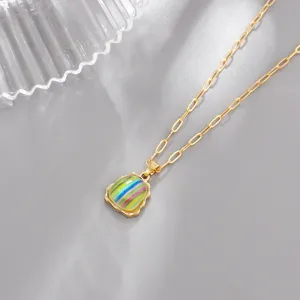 Primer plano de un elegante collar con colgante de acrílico arcoíris y cadena dorada fina.