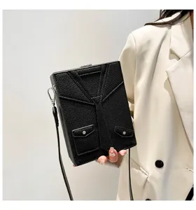 Dettaglio di una borsa a tracolla nera in pelle dal design originale con cravatta da abito.