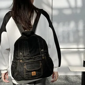 Detailed view of the black denim backpack worn, showing pocket and retro patch design.