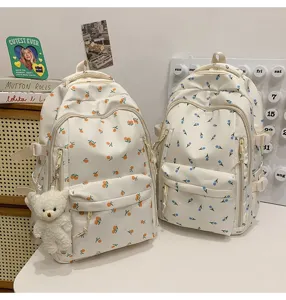 Detail view of cute floral student backpacks with lovely fruit prints and a cute bear pendant.