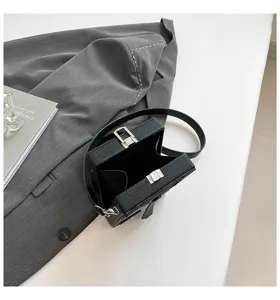 Primo piano dettagliato della borsa a tracolla nera a scatola con design unico e serratura.