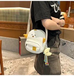Detail view of cute cartoon chicken canvas crossbody bag with yellow wings and moon pendant.