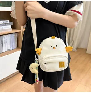 Cute little chicken cartoon cross-body bag detail, showing canvas texture and plush pendant.