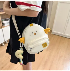 Close-up of cute cartoon chick crossbody bag with yellow 3D wings and plush moon pendant.