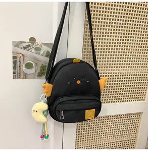 Cute black chicken crossbody bag detail showing embroidered eyes, wings, and plush pendant.