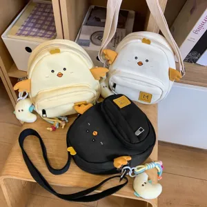Detailed view of cute cartoon chick crossbody bags in yellow, white and black canvas styles.